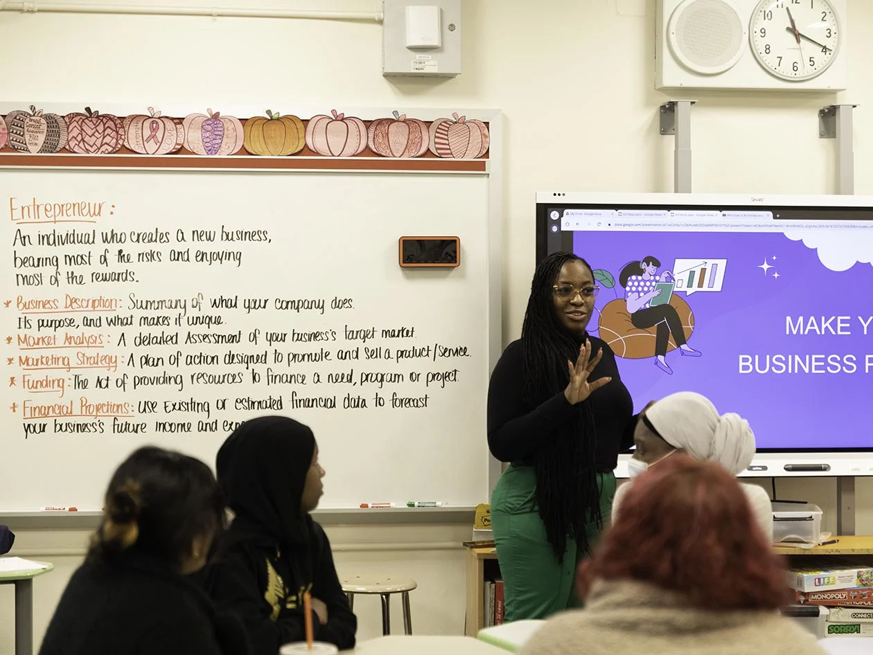 Shenequa Merchant teaches the principles of entrepreneurship in front of a classroom with girls. (Photo by Alison Bert)